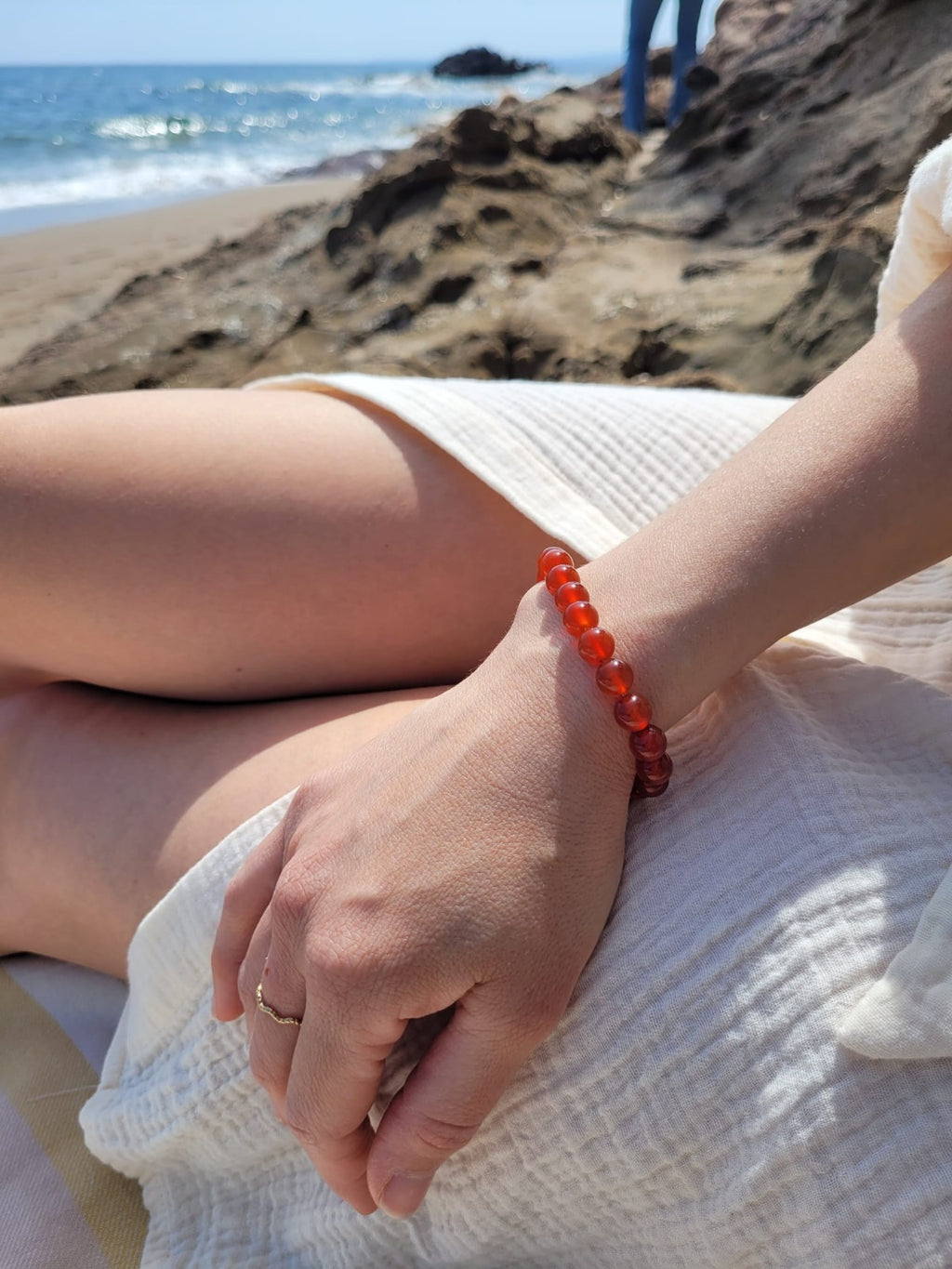 Bracelet en agate cornaline naturelle porté au poignet sur la plage